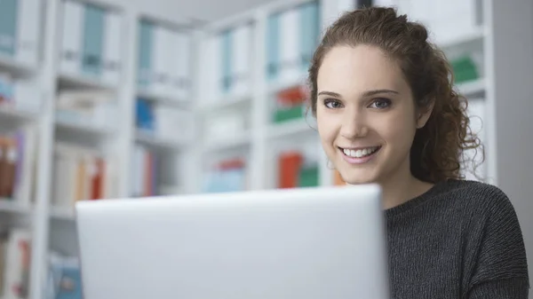 Menina estudante sorrindo se conectando com um laptop — Fotografia de Stock