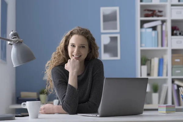 Young woman sitting at desk and posing — Stock Photo, Image