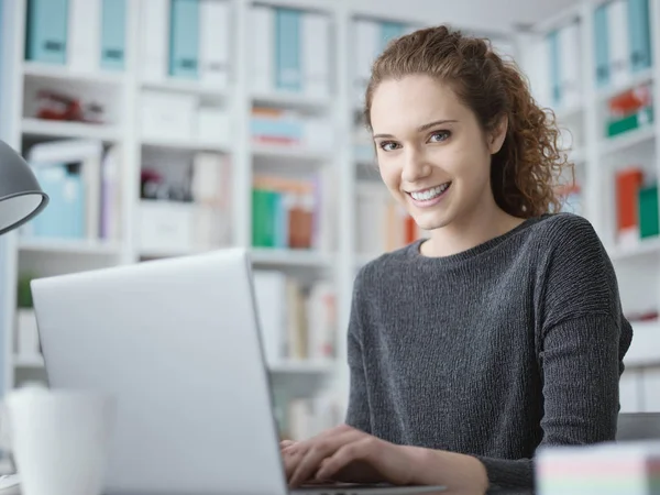 Chica estudiante sonriente conectar con un ordenador portátil — Foto de Stock