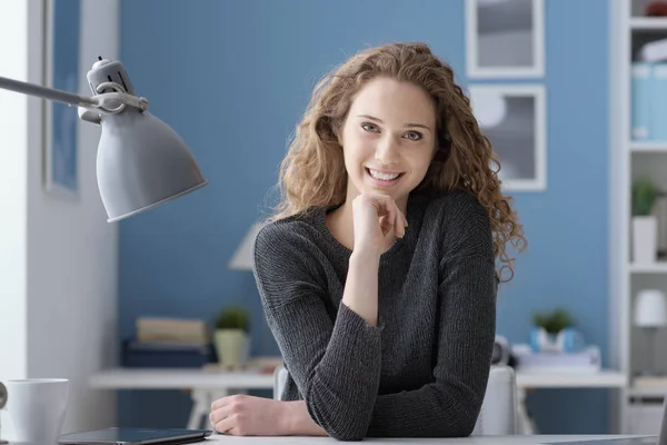 Ung kvinna sitter vid skrivbord och poserar — Stockfoto