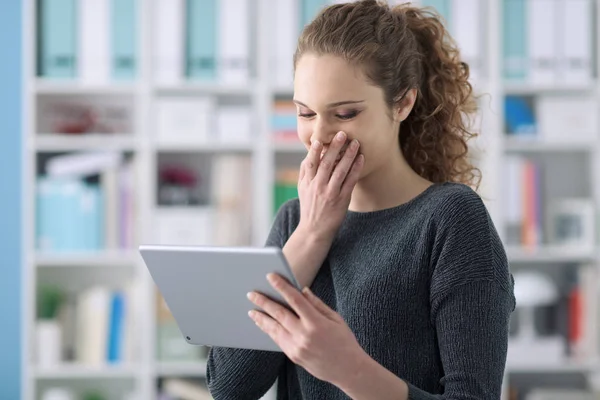 Mujer feliz usando una tableta y riéndose — Foto de Stock