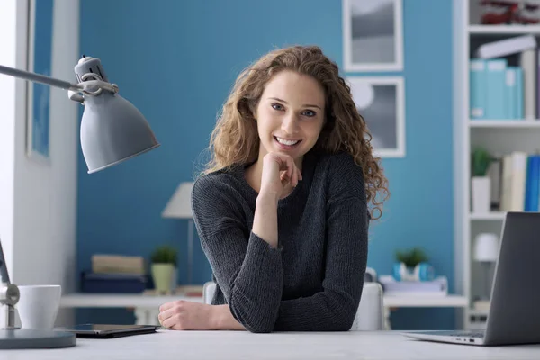 Jonge vrouw zit aan Bureau en poseren — Stockfoto