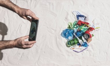 Sahilde atık kirliliği bir resim çeken adam