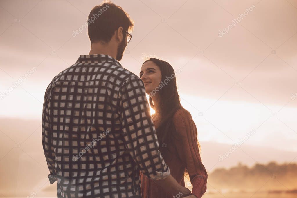 Young loving couple holding hands at sunset