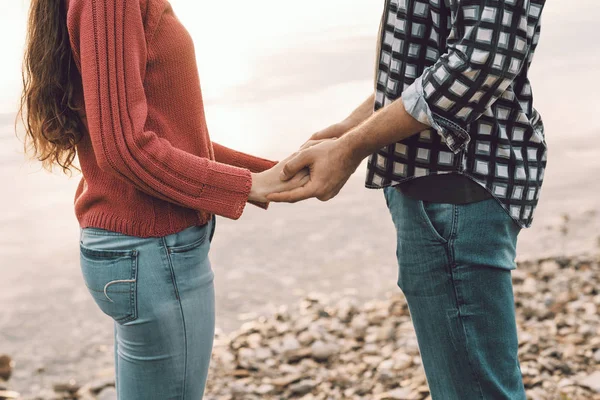 Süßes junges Paar hält Händchen am See — Stockfoto