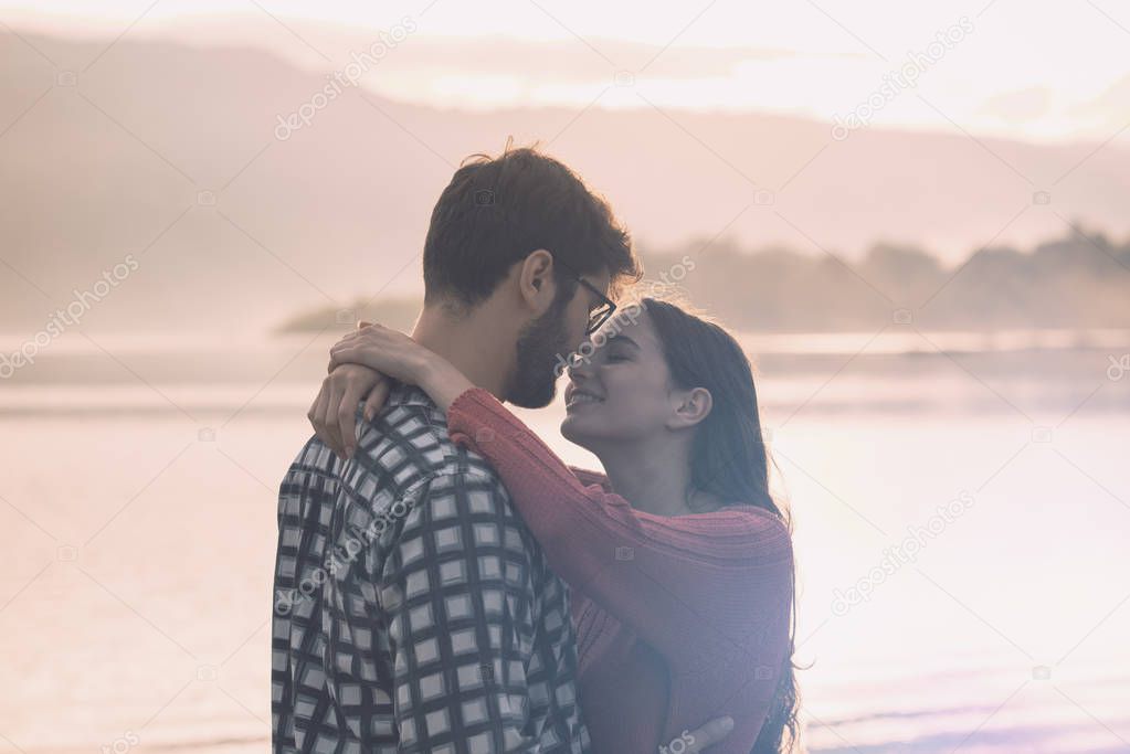 Young romantic couple kissing at sunset