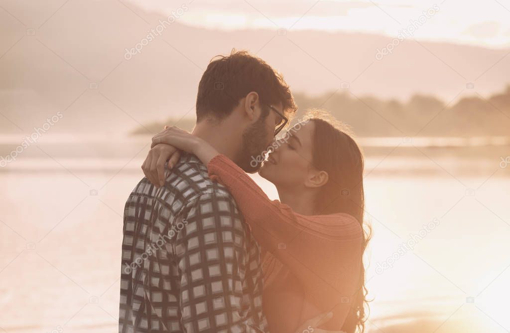 Young romantic couple kissing at sunset