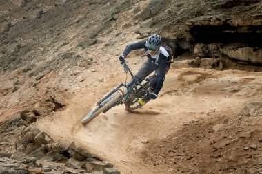 Yokuş aşağı bir MTB binicisi, arka planda Pasifik Okyanusu ve Lima şehrinin görkemli manzarasıyla El Morro Solar 'ın engebeli hatlarını oyuyor..
