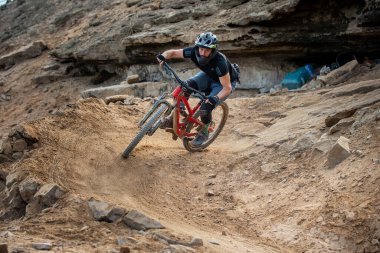 Yokuş aşağı bir MTB binicisi, arka planda Pasifik Okyanusu ve Lima şehrinin görkemli manzarasıyla El Morro Solar 'ın engebeli hatlarını oyuyor..