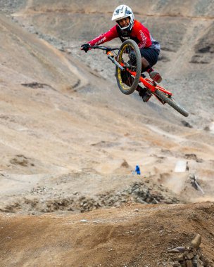 Yokuş aşağı bir MTB binicisi, arka planda Pasifik Okyanusu ve Lima şehrinin görkemli manzarasıyla El Morro Solar 'ın engebeli hatlarını oyuyor..