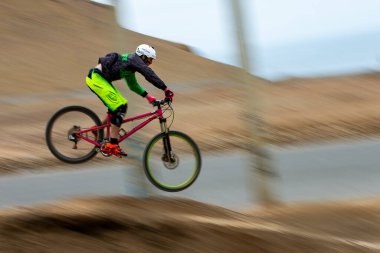 Yokuş aşağı bir MTB binicisi, arka planda Pasifik Okyanusu ve Lima şehrinin görkemli manzarasıyla El Morro Solar 'ın engebeli hatlarını oyuyor..