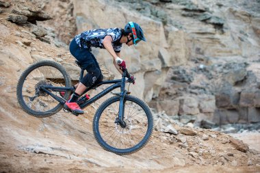 Yokuş aşağı bir MTB binicisi, arka planda Pasifik Okyanusu ve Lima şehrinin görkemli manzarasıyla El Morro Solar 'ın engebeli hatlarını oyuyor.