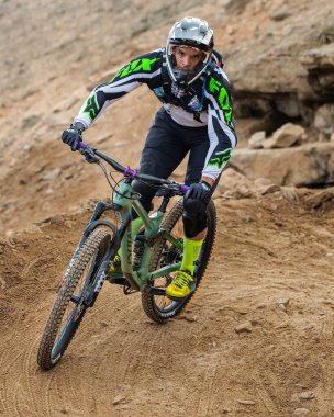 Yokuş aşağı bir MTB binicisi, arka planda Pasifik Okyanusu ve Lima şehrinin görkemli manzarasıyla El Morro Solar 'ın engebeli hatlarını oyuyor.