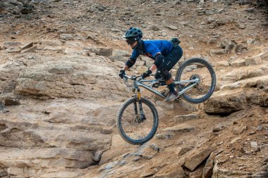 Yokuş aşağı bir MTB binicisi, arka planda Pasifik Okyanusu ve Lima şehrinin görkemli manzarasıyla El Morro Solar 'ın engebeli hatlarını oyuyor.