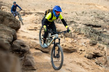 Yokuş aşağı bir MTB binicisi, arka planda Pasifik Okyanusu ve Lima şehrinin görkemli manzarasıyla El Morro Solar 'ın engebeli hatlarını oyuyor.