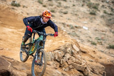 Yokuş aşağı bir MTB binicisi, arka planda Pasifik Okyanusu ve Lima şehrinin görkemli manzarasıyla El Morro Solar 'ın engebeli hatlarını oyuyor.