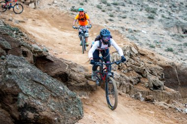 Yokuş aşağı bir MTB binicisi, arka planda Pasifik Okyanusu ve Lima şehrinin görkemli manzarasıyla El Morro Solar 'ın engebeli hatlarını oyuyor.