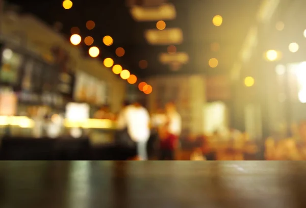 Ahşap Masa üst parti nuru ile bulanıklık pub ya da karanlık gece arka planda bar