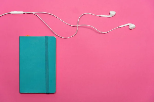 Πολύχρωμο Μπλε Σημειωματάριο Λευκά Ακουστικά Για Ακούσετε Μουσική Όταν Εργασίας — Φωτογραφία Αρχείου