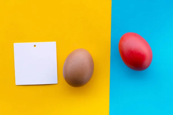 Vörös és nyers húsvéti tojást színes sárga és kék papírra, és — Stock Fotó