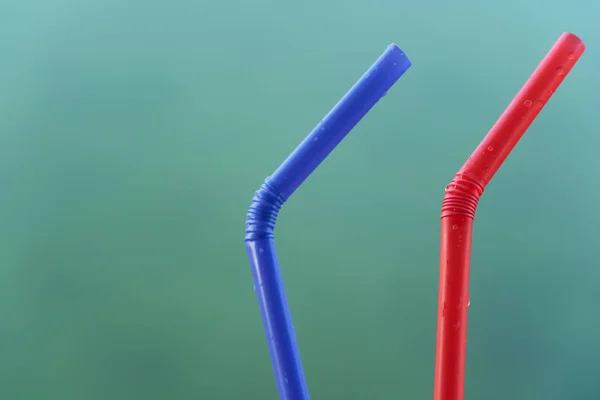 red and blue plastic straw on green blue background environment