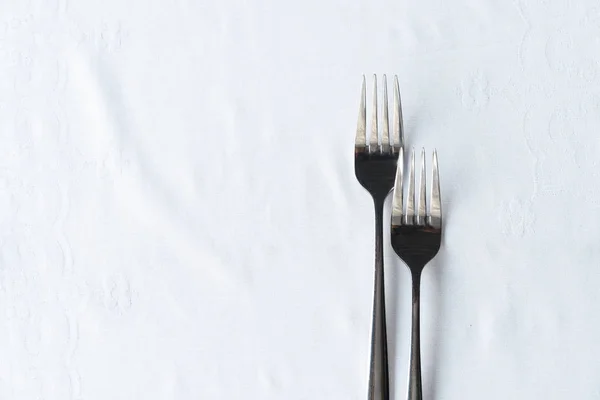 Dos de metal tenedor de acero inoxidable sobre mantel blanco para alimentos d —  Fotos de Stock