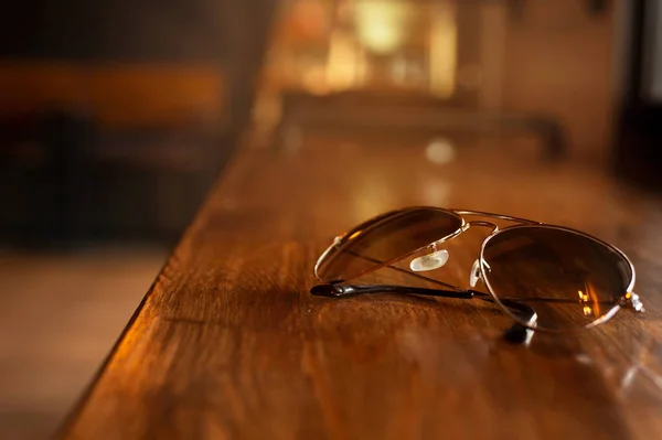Gafas de sol clásicas sobre fondo de mesa de madera marrón barra de luz —  Fotos de Stock