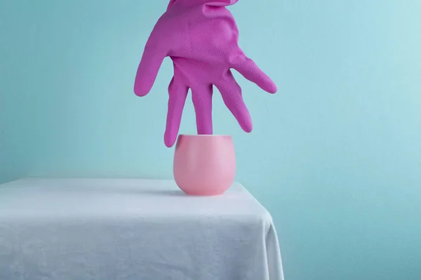 Sıcak çay pastel pembe seramik bardak. Renkli lastik eldiven, mavi duvar, fantezi arka plan.