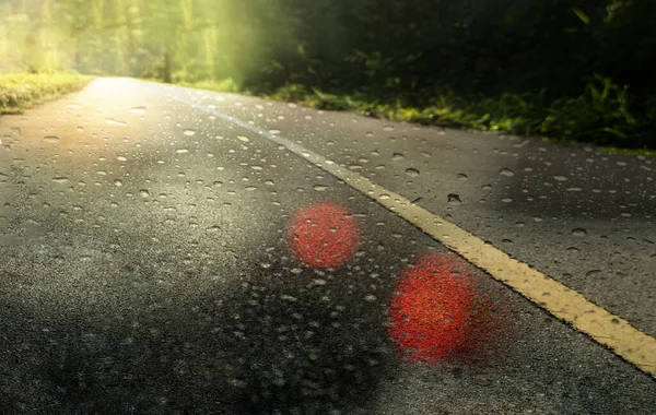 city dark asphalt road or street in the raining day with water drop and soft green orange light background