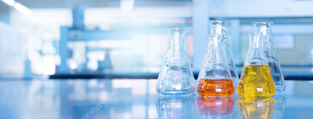 orange yellow solution in science glass flask win blue research chemistry laboratory banner background