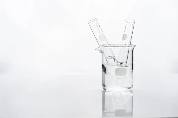 test tube in glass beaker with water in white chemistry science laboratory background