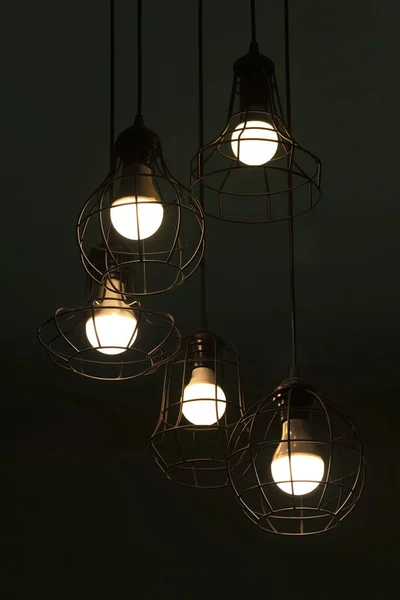 hanging classic black metal light bulb in night time interior on dark green background