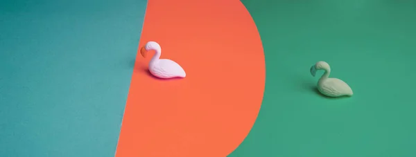 カラフルな紙の上の鳥のピンクグリーンプラスチックモデル現代的なデザインのバナーの背景 — ストック写真