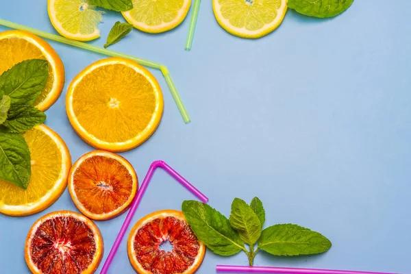 Portakal, limon, kırmızı portakal ve nane yaprakları renkli yuvarlak dilim. Payet kokteyller için. Mavi bir arka plan üzerinde.