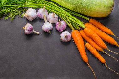 Sebze yemek pişirmek için. Sonbaharda hasat. Kabak, havuç ve sarımsak. Organik gıda. Gri arka plan. Metnin altında yer.