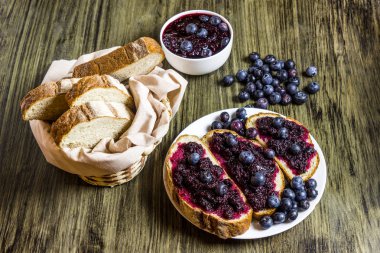 Böğürtlenli reçel. Böğürtlenli reçel sandviç. Ev reçel yaptı. Bir kavanoz ve bir kase içinde reçel. Ekmek. Taze yaban mersini. Rustik tarzı. Ahşap masa.