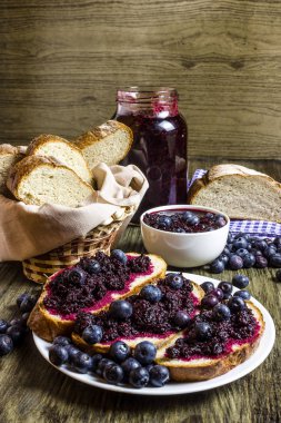 Böğürtlenli reçel. Böğürtlenli reçel sandviç. Ev reçel yaptı. Dilimlenmiş ekmek. Taze yaban mersini. Rustik tarzı. Ahşap masa.