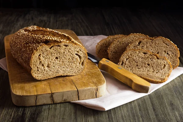 Whole grain bread with sesame on a wooden board.