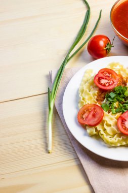 Taze domates ve soğan beyaz bir tabak makarna.