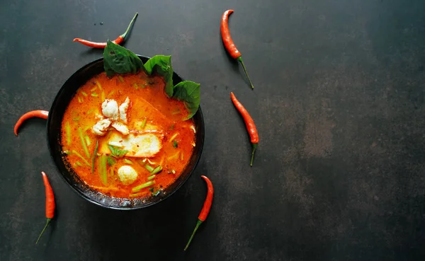 Tayland yemekleri konsepti. Tayland mutfağı tabağı. Tom yum çorbasının ve biberin en üstteki görünümü sağ tarafta metin için kopyalama alanı olan masa koyu arkaplanı üzerinde