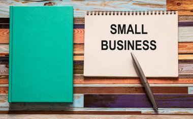 çok renkli ahşap arka plan defterinde küçük bir iş yeri ve turkuaz bir defter var.