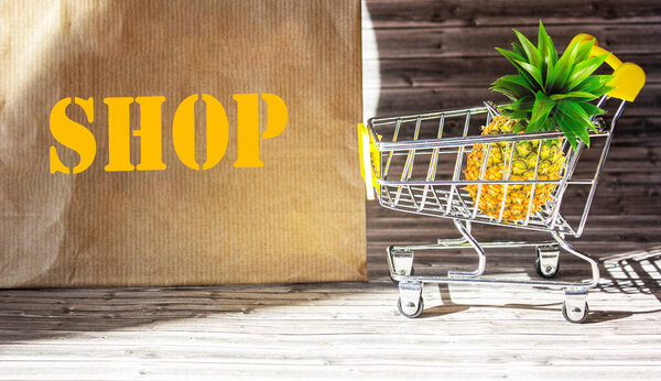 Shopping basket and pineapple on a brown background and a bag with the word Shop