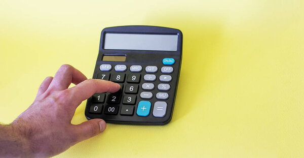 on a yellow background male hand shows on a calculator