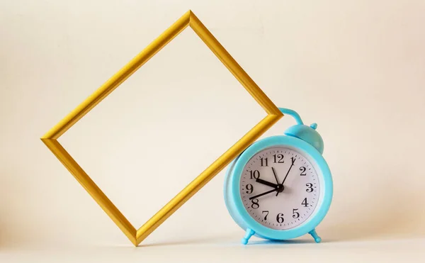 A blue alarm clock is placed on a white background with a frame for recording or photograph. Time management concept Writing notes at important moments. Good memory. There is room for placing text on a sheet of paper.