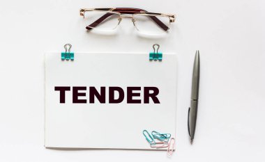 Tender, not defterinden haber var. Beyaz arkaplanda gözlük, kalem ve ataç.
