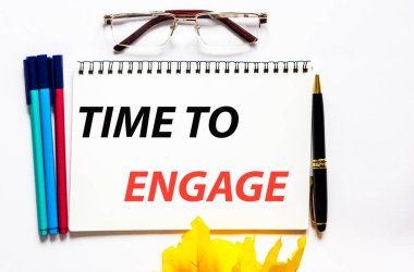 Bağlanma zamanı, metin bir deftere yazılır, gözlük, kalem ve keçeli kalemlerin yanında beyaz bir arkaplanda..