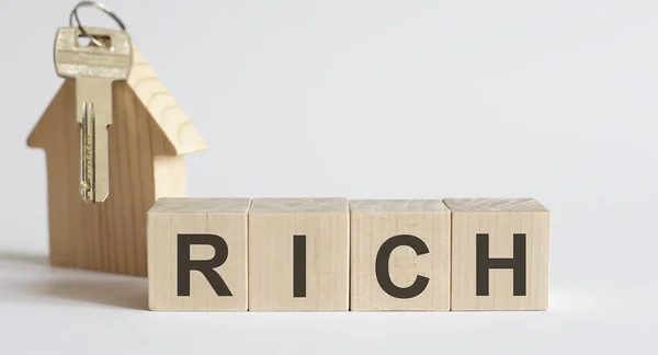 Wooden blocks with the word RICH , house. The concept of the high cost of rent for an apartment or home.Real estate market.