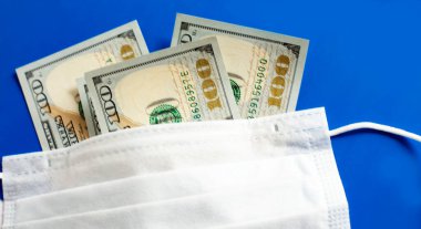 Tıbbi maske, mavi arka planda tıbbi koruyucu maske. Cerrahi maske örtüsü. Amerikan doları..