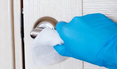 Coronavirus COVID-19 'un yayılmasını önleyecek eylemler, kapı kolunun dezenfekte edilmesi. Eldivenler, kapı kolunu dezenfektanla siler.