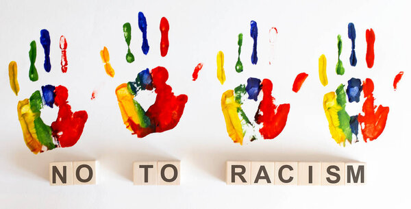 Word NO RACISM on wooden blocks and color hands